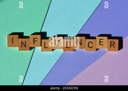 Influenceur, mot en lettres de l'alphabet en bois isolées sur fond coloré. Banque D'Images