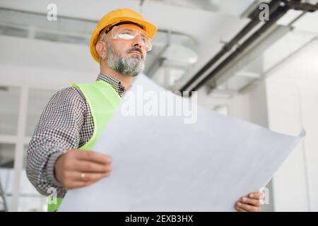 Ingénieur caucasien mature qualifié dans le projet de vérification de hardhat de construction Banque D'Images