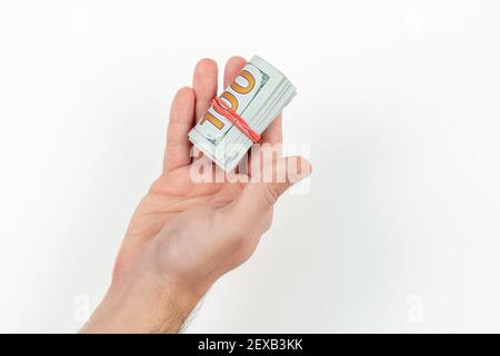 Un homme tient dans sa main de l'argent dans un rouleau attaché avec un groupe isolé sur un fond blanc. Devise AMÉRICAINE Banque D'Images