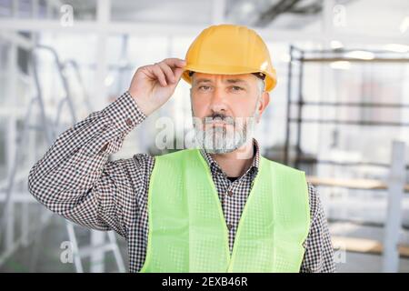 Portrait d'un architecte mature dans un casque posé à l'intérieur Banque D'Images