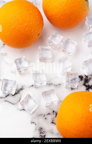 Vue aérienne de trois oranges avec glace, sur marbre blanc, verticalement Banque D'Images