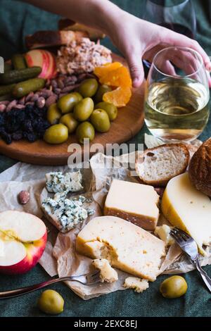 Une main pour le vin blanc dans une planche à fromage etartiner Banque D'Images