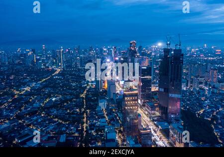 Vue panoramique aérienne du paysage urbain moderne avec des gratte-ciels de nuit et des quartiers résidentiels dans la nuit bleue de Jakarta, Indonésie Banque D'Images