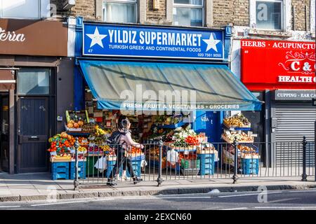 Deux femmes passent devant le supermarché turc et grec Yildiz sur Junction Road, Islington, Londres, Royaume-Uni Banque D'Images