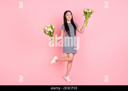 Pleine longueur photo de taille de corps de joie pleine fille tenue deux bouquets de tulipes isolés sur fond rose pastel Banque D'Images