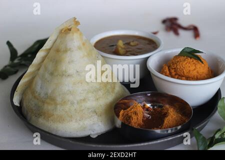 Dosa de ghee fin et croustillante avec sambar, chutney de noix de coco et Molaha Podi. DOSA est servi en forme de tente. Un petit déjeuner indien du Sud. Prise de vue sur fond blanc Banque D'Images