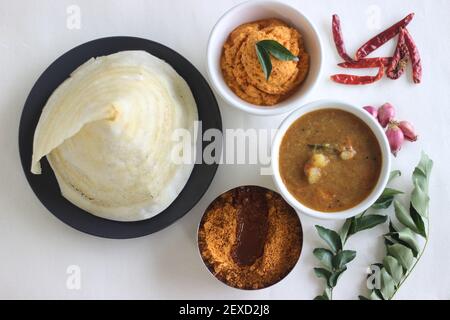 Dosa de ghee fin et croustillante avec sambar, chutney de noix de coco et Molaha Podi. DOSA est servi en forme de tente. Un petit déjeuner indien du Sud. Prise de vue sur fond blanc Banque D'Images