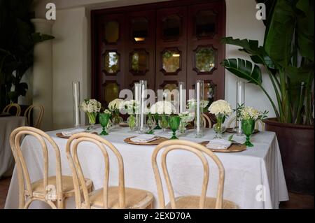 Table avec serviette et verts, assiettes en bois et verres verts, vases avec fleurs blanches et bougies Banque D'Images