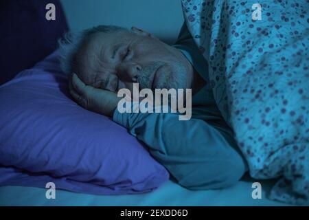 Dormant homme senior dans le lit pendant minuit, concept de style de vie Banque D'Images