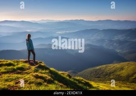 Fille sur le pic de montagne regardant de belles montagnes au coucher du soleil Banque D'Images