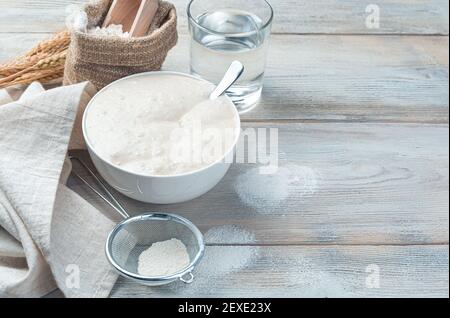 Levain de blé, farine et eau sur fond de bois clair. Le concept de fabrication du pain. Banque D'Images