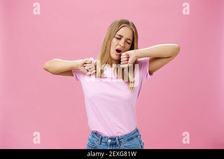 Trop fatiguée pour travailler aujourd'hui. Paresseux et épuisé jeune étudiante attrayante faisant les devoirs toute la nuit bâilling avec les yeux fermés tout en étirant les mains Banque D'Images