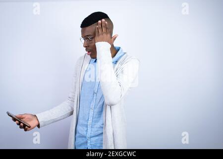 Jeune homme afro-américain élégant portant des vêtements décontractés pour bavarder le téléphone avec une expression inquiète Banque D'Images