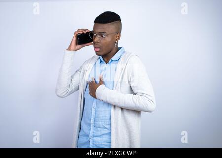 Jeune homme afro-américain élégant portant des vêtements décontractés qui parlent le téléphone avec une expression inquiète Banque D'Images