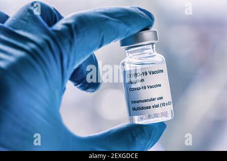 Main dans un gant bleu contenant le flacon du vaccin Covid-19 Banque D'Images