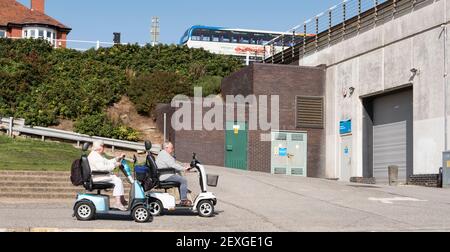 Deux personnes âgées sur des scooters de mobilité Banque D'Images