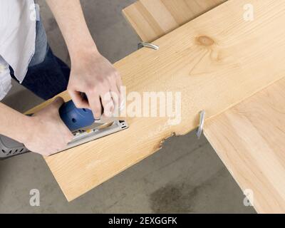 Image en hauteur d'un homme coupant une feuille de bois planche Banque D'Images