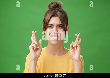 Gros plan de la femme nerveuse priant pour avoir une réponse positive croisant les doigts pour la bonne chance mordant la lèvre inférieure anxieusement et le frowning étant inquiet Banque D'Images