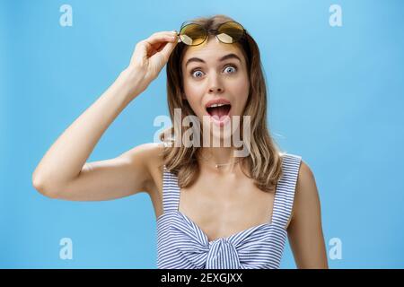 Une femme qui marche à travers le steet rencontre un ami qui prend des lunettes de soleil et regarde surpris de l'ouverture de la caméra bouche à dire salut avec large joyeux sourire et content Banque D'Images