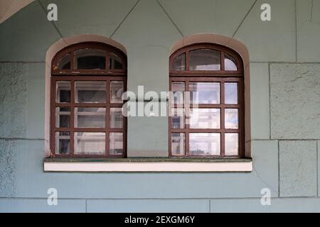 Paire de fenêtres vintage dans des fixations en bois faites de carrés sur un mur en brique plâtrée d'une vieille maison Banque D'Images