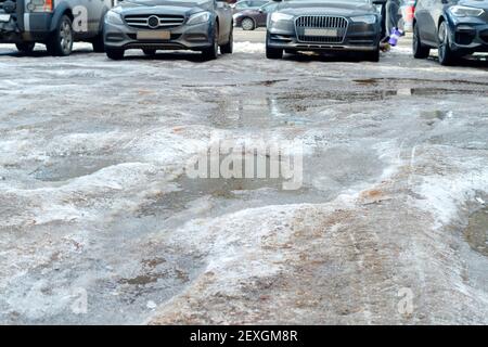 Flaques de neige et de glace fondantes sur l'asphalte. Routes urbaines non dégagées au début du printemps. Banque D'Images