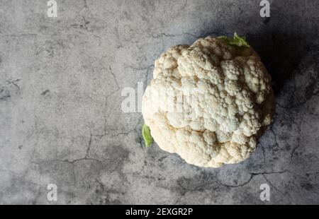 Image en hauteur de la tête de chou-fleur sur fond de pierre grise. Banque D'Images