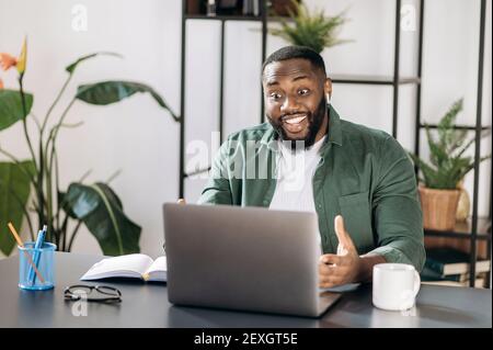 Sympathique afro-américain réussi freelance homme ou homme d'affaires regardant l'ordinateur portable heureusement, a reçu un bon message ou a fait une bonne affaire Banque D'Images