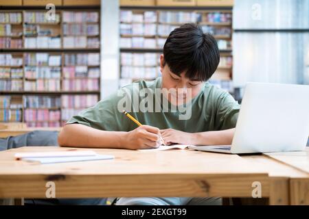 Jeune étudiant de collage utilisant un ordinateur et un appareil mobile étudiant Banque D'Images