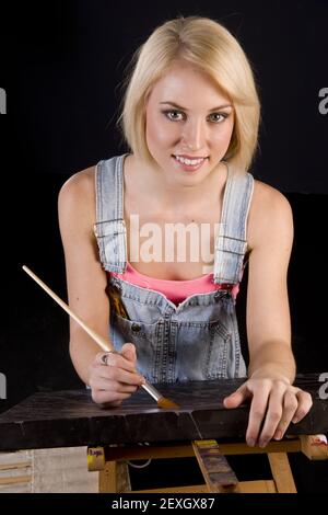 Happy Blond Woman apporte des touches de finition à la peinture sur Easel Banque D'Images