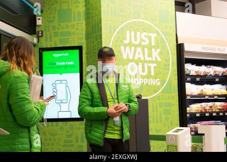 Deux employés en blouson vert se tiennent à l'entrée d'Amazon Fresh, son premier magasin avec « Just Walk Out » à Ealing Londres, Royaume-Uni Banque D'Images