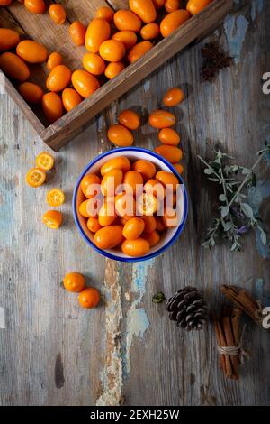 Vue de dessus des kumquats frais dans l'assiette sur le fond en bois naturel. Cumquat ou kumquat. Banque D'Images