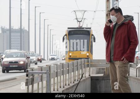 Budapest, Hongrie. 4 mars 2021. Un homme portant un masque parle sur son téléphone portable à une station de tramway à Budapest, Hongrie, le 4 mars 2021. Le gouvernement hongrois a présenté jeudi un ensemble de règles plus strictes pour lutter contre la troisième vague de pandémie, les nouvelles infections quotidiennes ayant dépassé les 6,000 000, un niveau jamais vu depuis novembre dernier. Credit: Attila Volgyi/Xinhua/Alay Live News Banque D'Images