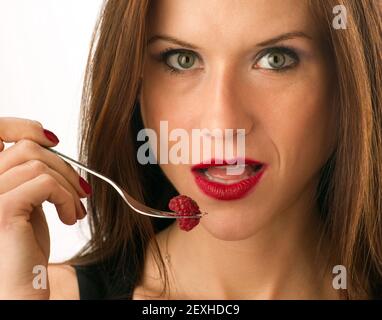 La femme mange des fruits crus aliments framboises sur la fourchette Banque D'Images