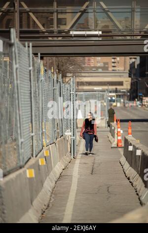 Minneapolis, Minnesota, États-Unis. 4 mars 2021. Une femme qui descend sur la 4e avenue S regarde à travers l'escrime qui a été mise en place en préparation pour le Minnesota v Derek Chauvin tiral qui doit commencer par la sélection du jury le 8 mars et le procès à partir du 29 mars. Credit: Chris Juhn/ZUMA Wire/Alay Live News Banque D'Images