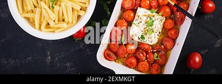 Fetapasta. Recette de pâtes à la mode de la Fêta virale faite de tomates cerises, de feta, d'ail et d'herbes dans un plat de cocotte. Vue de dessus, bannière, copie sp Banque D'Images