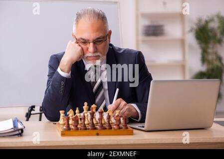 Un vieux employé d'homme d'affaires jouant aux échecs sur le lieu de travail Banque D'Images