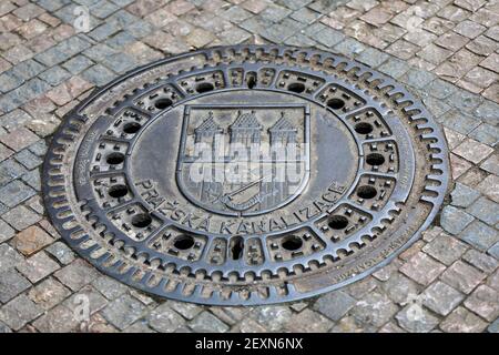 Prague, République tchèque - 13 avril 2018 : couverture du trou d'homme de Prazska Kanalizace avec les armoiries de Prague et la tour du pont Banque D'Images