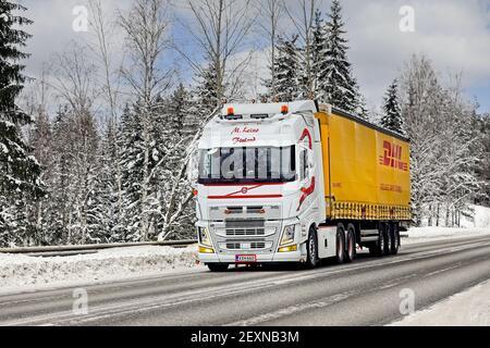 Le camion Volvo FH blanc sur mesure M. Leino tire la remorque DHL sur l'autoroute 52 par temps froid. Salo, Finlande. 12 février 2021. Banque D'Images