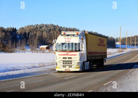 Le camion Volvo FH blanc sur mesure M. Leino tire la remorque DHL sur l'autoroute 52 par beau temps d'hiver. Salo, Finlande. 11 février 2021. Banque D'Images