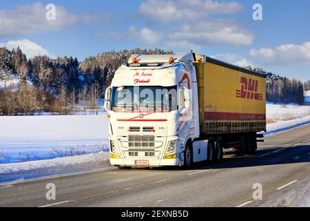 Le camion Volvo FH blanc sur mesure M. Leino tire la remorque DHL sur l'autoroute 52 par beau temps d'hiver. Salo, Finlande. 11 février 2021. Banque D'Images