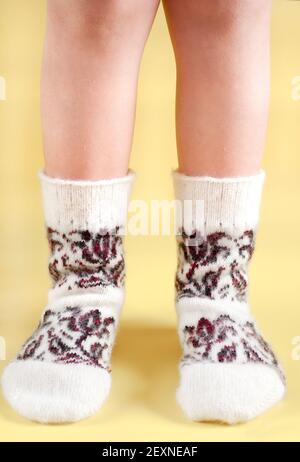 Pieds d'enfant en chaussettes de laine sur fond jaune Banque D'Images