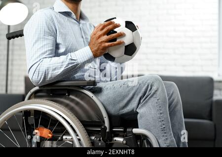 Homme invalide ou handicapé assis sur un fauteuil roulant et tenant le football bille Banque D'Images