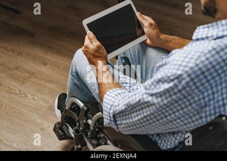 Jeune homme afro-américain handicapé assis en fauteuil roulant et en utilisant tablette numérique Banque D'Images