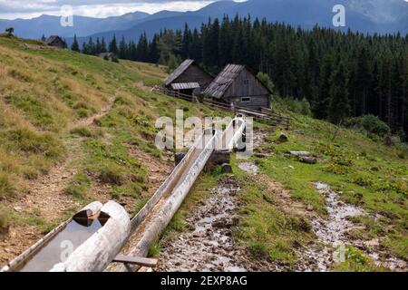 Un canal d'irrigation rural s'écoulant à travers des tuyaux en bois dans le village Banque D'Images