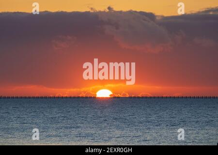 Shoeburyness, Essex. 5 mars 2021 - Sunrise, Thames Estuary, Royaume-Uni - UNE banque de nuages à l'horizon est a partiellement obscurci le soleil lorsqu'il s'est levé au-dessus de l'estuaire de la Tamise, bien qu'elle ait aidé à créer des éclaboussures momentanées de couleurs vives. L'ancien boom de la défense de la Guerre froide est défait par rapport à l'horizon brillant crédit: Timothy Smith/Alay Live News Banque D'Images