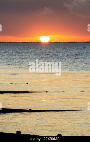 Shoeburyness, Essex. 5 mars 2021 - Sunrise, Thames Estuary, Royaume-Uni - UNE banque de nuages à l'horizon est a partiellement obscurci le soleil lorsqu'il s'est levé au-dessus de l'estuaire de la Tamise, bien qu'elle ait aidé à créer des éclaboussures momentanées de couleurs vives. L'ancien boom de la défense de la Guerre froide est défait par rapport à l'horizon brillant crédit: Timothy Smith/Alay Live News Banque D'Images