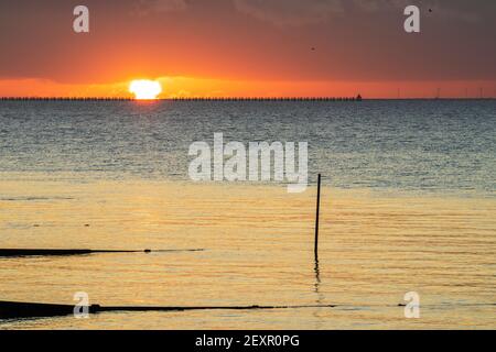 Shoeburyness, Essex. 5 mars 2021 - Sunrise, Thames Estuary, Royaume-Uni - UNE banque de nuages à l'horizon est a partiellement obscurci le soleil lorsqu'il s'est levé au-dessus de l'estuaire de la Tamise, bien qu'elle ait aidé à créer des éclaboussures momentanées de couleurs vives. L'ancien boom de la défense de la Guerre froide est défait par rapport à l'horizon brillant crédit: Timothy Smith/Alay Live News Banque D'Images