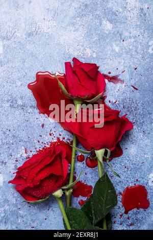 Roses rouges et sang sur fond bleu texturé avec espace de copie et espace pour le texte Banque D'Images
