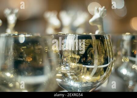 Gros plan d'un motif de cuillères de cerf en céramique blanc suspendu sur un verre avec beau bokeh doux en arrière-plan, espace de copie image festive en forme de cerf Banque D'Images