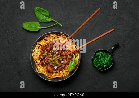 Bakmi ou Mie Ayam dans un bol noir sur une table en ardoise sombre. Cuisine indonésienne nouilles plat de viande. Plats et repas asiatiques traditionnels. Vue de dessus Banque D'Images